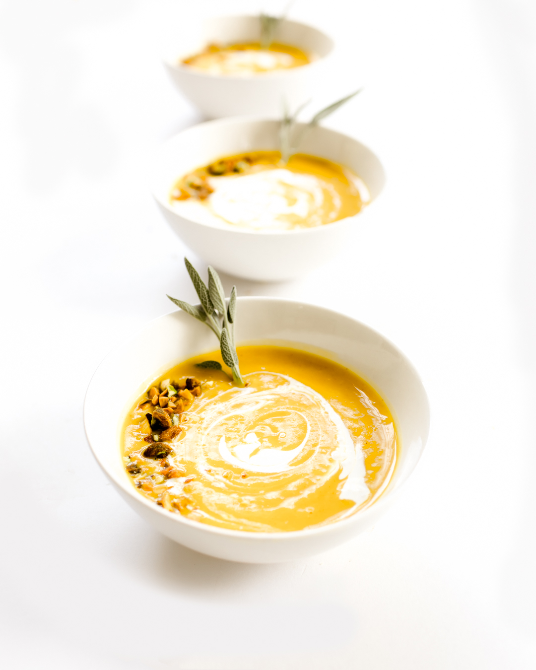 Butternut Squash Soup Bowls Topped with Herbs and Sour Cream Drizzle