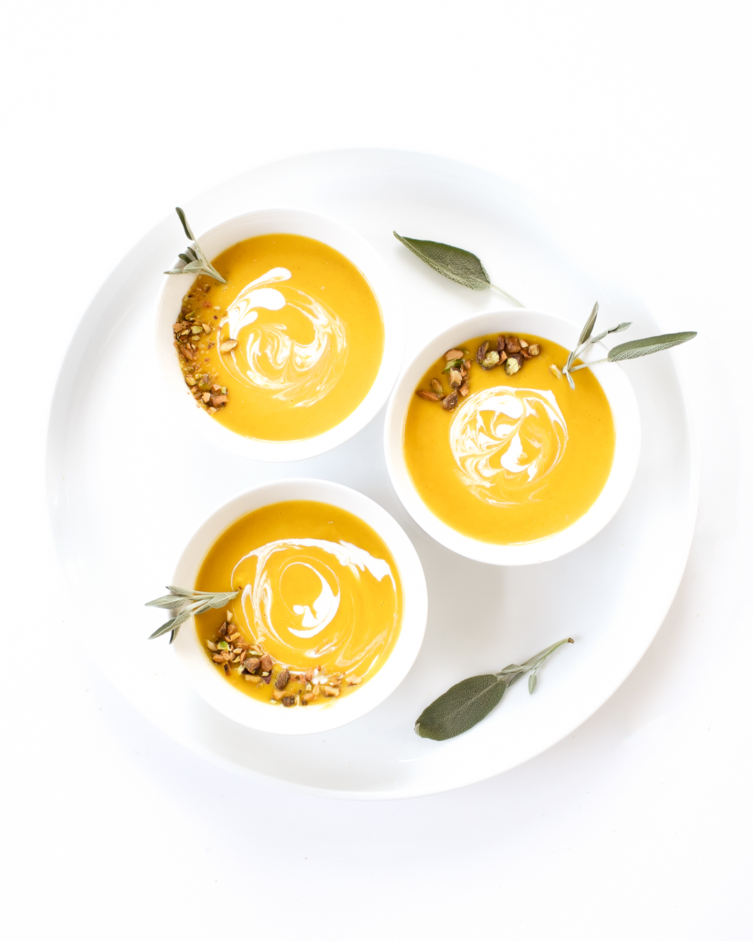 Butternut Squash Soup Bowls Topped with Herbs and Sour Cream Drizzle