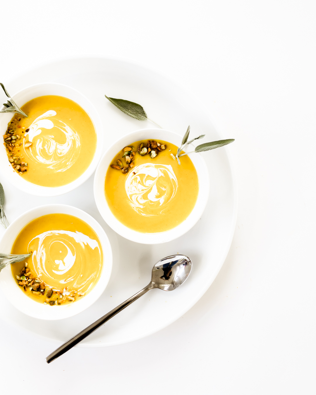 Butternut Squash Soup Bowls Topped with Herbs and Sour Cream Drizzle